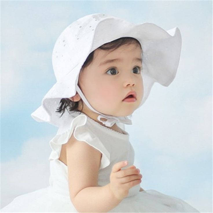 a baby wearing a white dress and bonnet