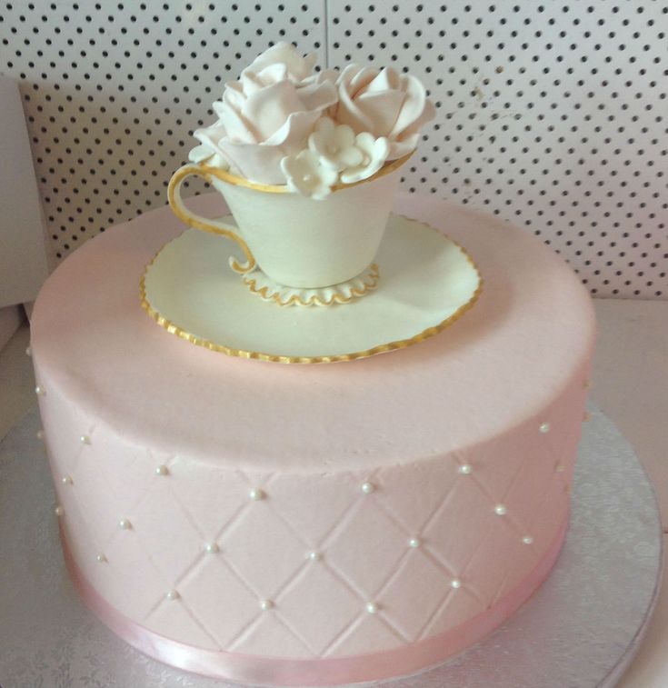 a pink cake with white frosting and gold trimmings on a silver platter