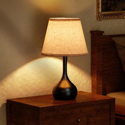 a lamp on a night stand next to a bed