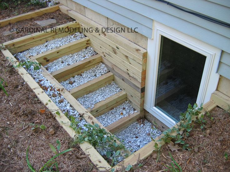 a dog house built into the side of a building with gravel and wood steps leading up to it