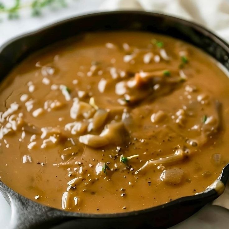 a black skillet filled with soup on top of a white cloth covered tablecloth