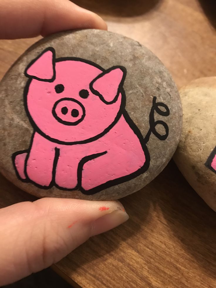 a hand holding a rock with a pig painted on it next to another rock that says i love you