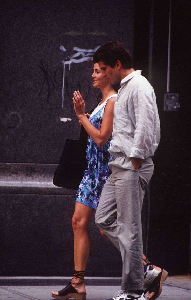 a man and woman are walking down the street with their hands in each other's pockets