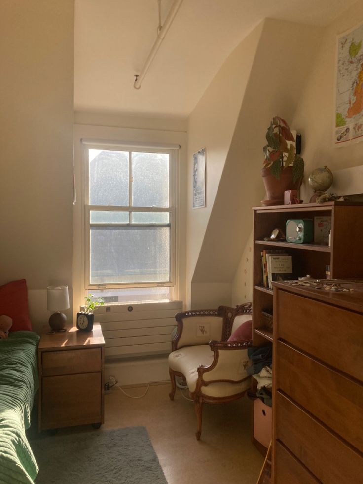 a bedroom with a bed, desk and chair in it next to a large window