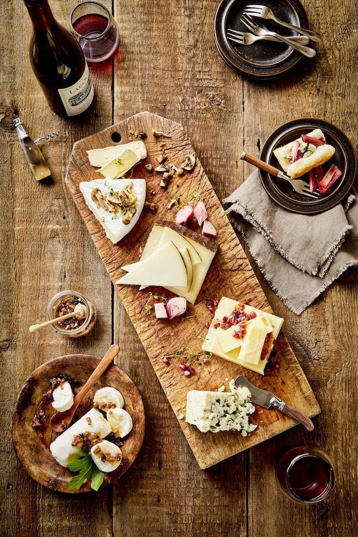 several different types of cheeses and wine on a wooden table