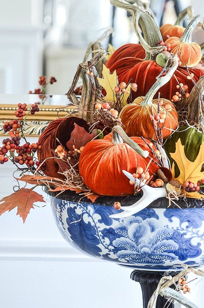 a blue and white vase filled with lots of pumpkins sitting on top of a table