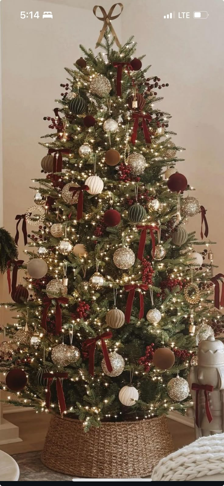 a decorated christmas tree with red and white ornaments in a wicker basket on the floor