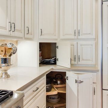 a kitchen with white cupboards and an open drawer in the middle that has utensils on it