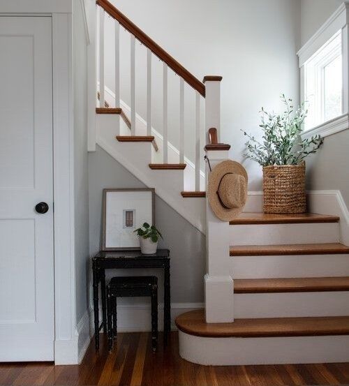 there is a hat on the stairs in this house with wood floors and white walls