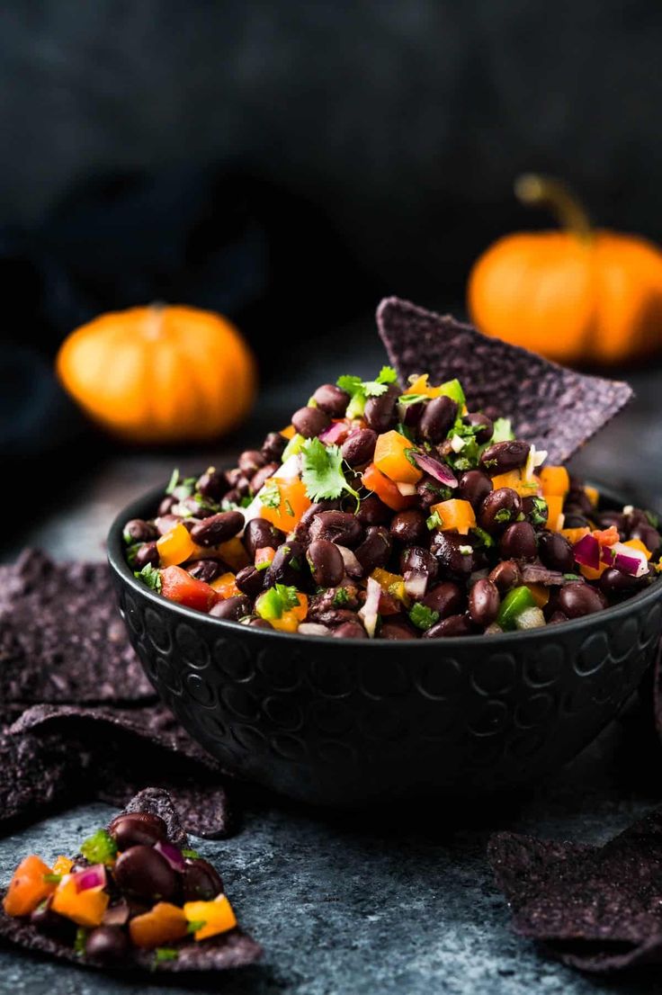 a bowl filled with black beans and veggies next to tortilla chips