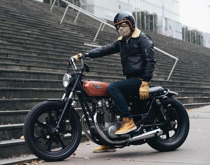 a man wearing a helmet and goggles sitting on a motorcycle in front of bleachers