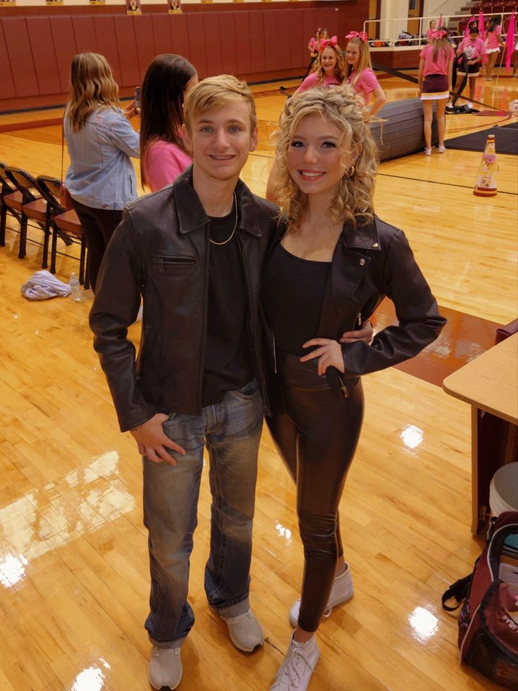 a man and woman standing next to each other on a hard wood floored court