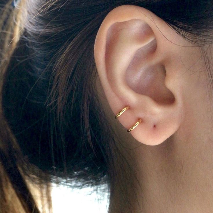 a close up of a person's ear with two small gold rings on it