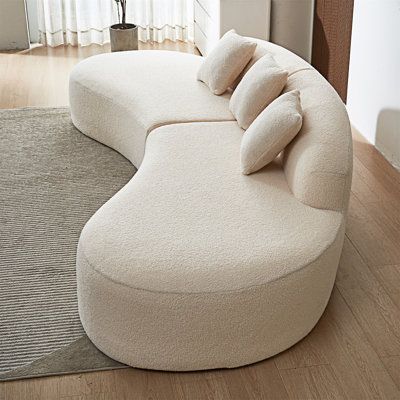 a large white couch sitting on top of a wooden floor next to a lamp and window