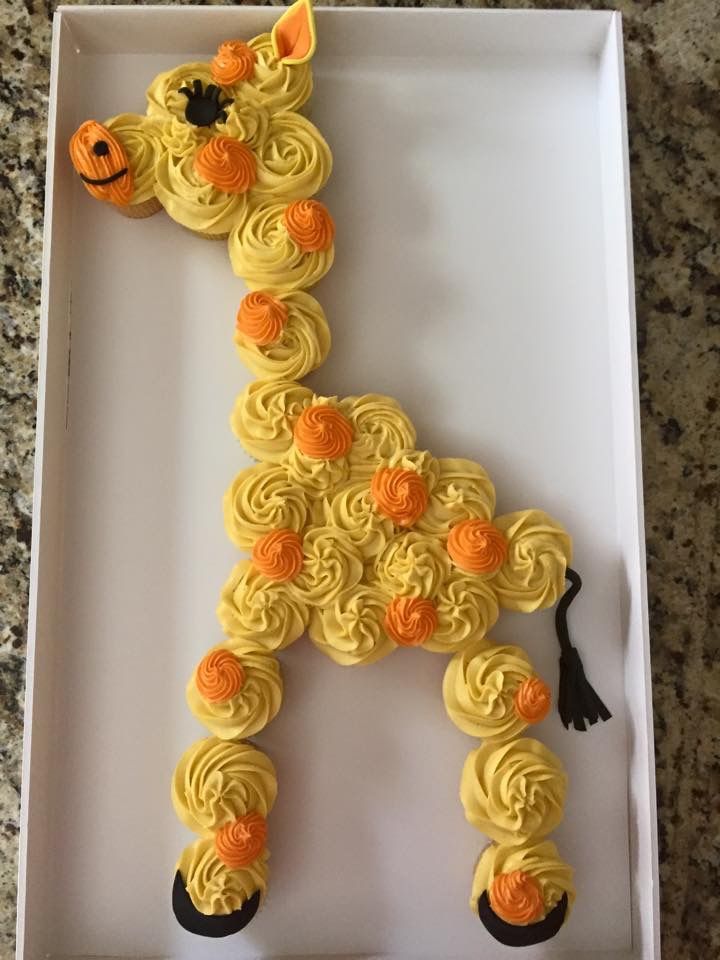 a cake in the shape of a giraffe with yellow frosting and orange flowers