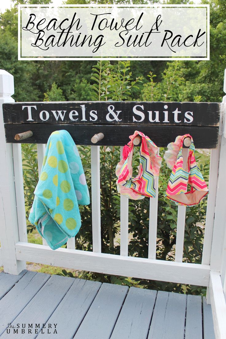 towels and blankets are hanging on the back of a white porch rail with text overlay that reads beach towel & bathing suit rack