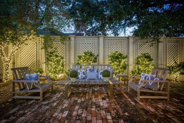 an outdoor seating area is lit up with string lights and decorative pillows on wooden chairs