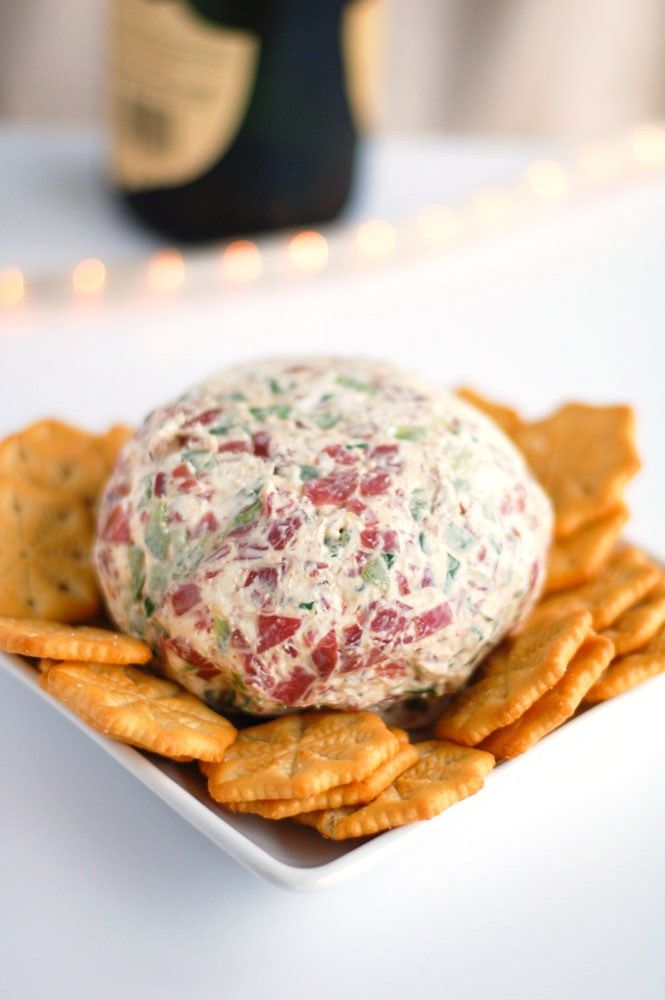 a cheese ball sitting on top of crackers in front of a bottle of wine