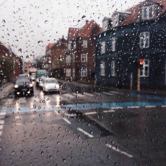 rain drops on the window as cars drive down a city street in front of buildings