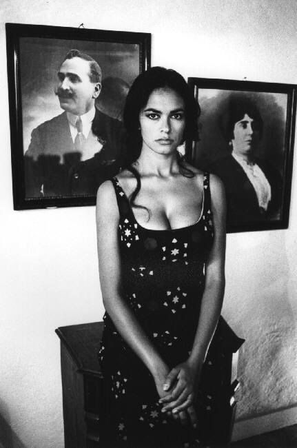 a black and white photo of a woman standing in front of two portraits