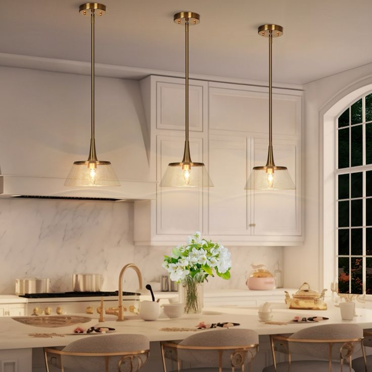 a kitchen filled with lots of counter top space and lights hanging from the ceiling above it