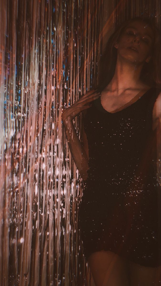 a woman standing in front of a curtain with rain drops on the wall behind her