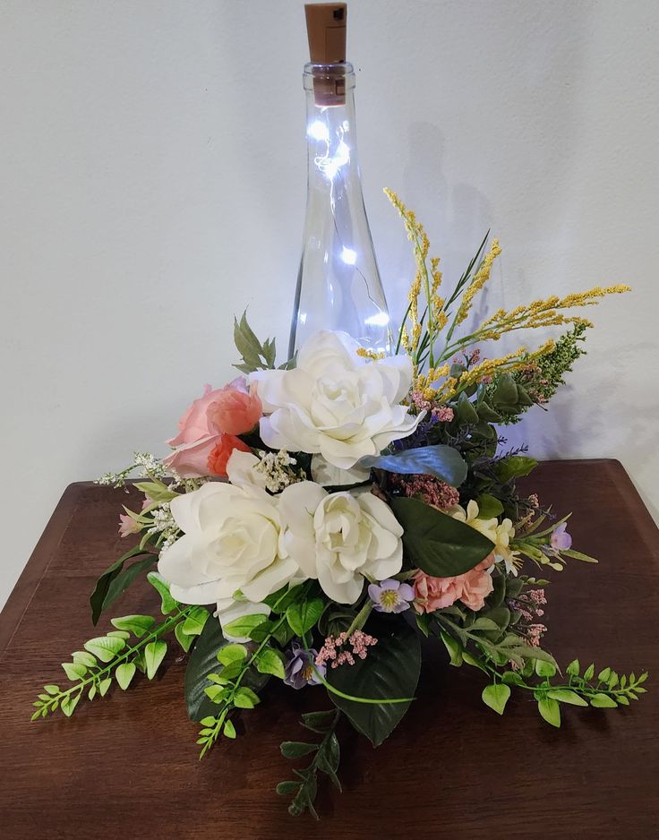 a bouquet of flowers on a table with a bottle in the backgrouf