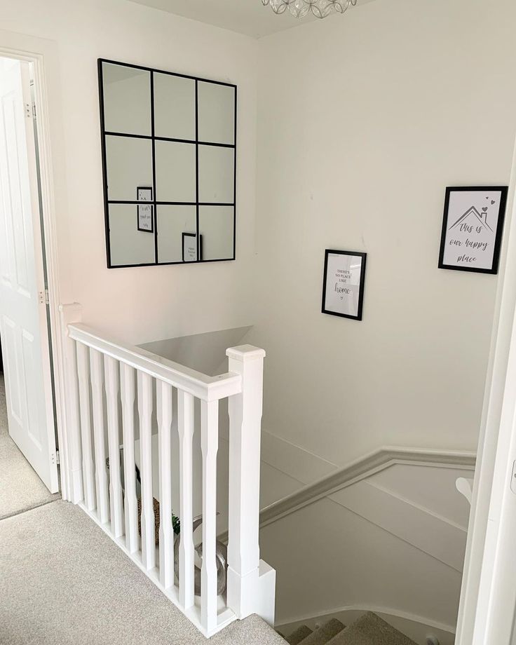 a white staircase with pictures on the wall and framed photos on the wall next to it