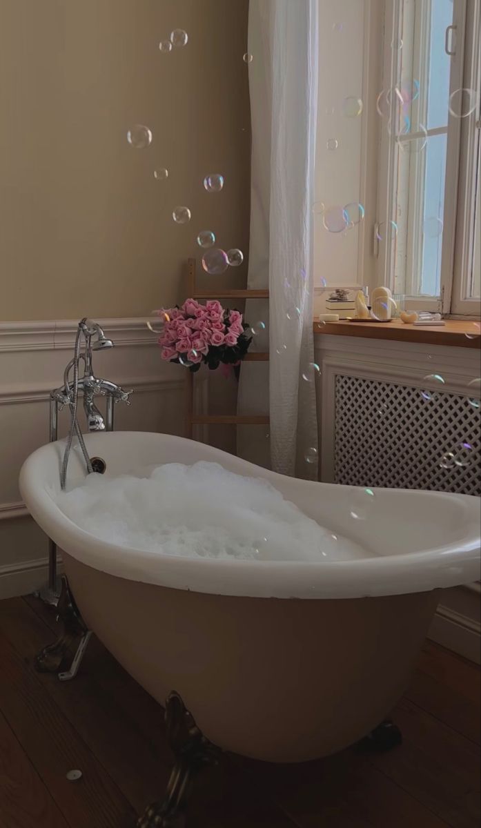 an old bathtub with soap bubbles floating in the air next to a window and radiator