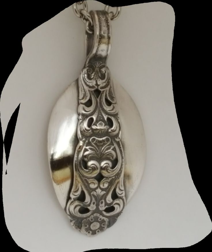 an ornate silver spoon is hanging from a chain on a white background with the words interest written below it