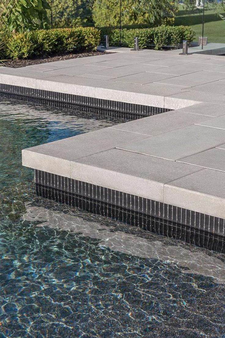 an outdoor swimming pool with water running through it and steps leading up to the edge