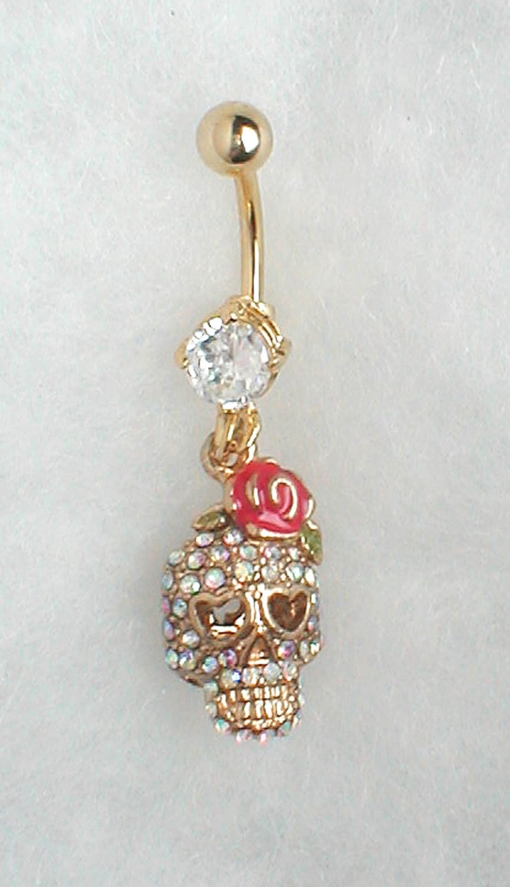 a gold colored belly ring with a crystal skull