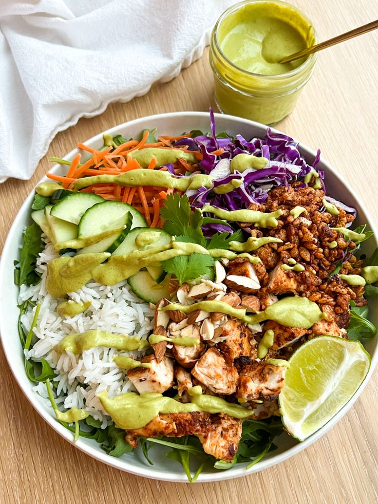 a white bowl filled with rice, meat and veggies next to a green smoothie