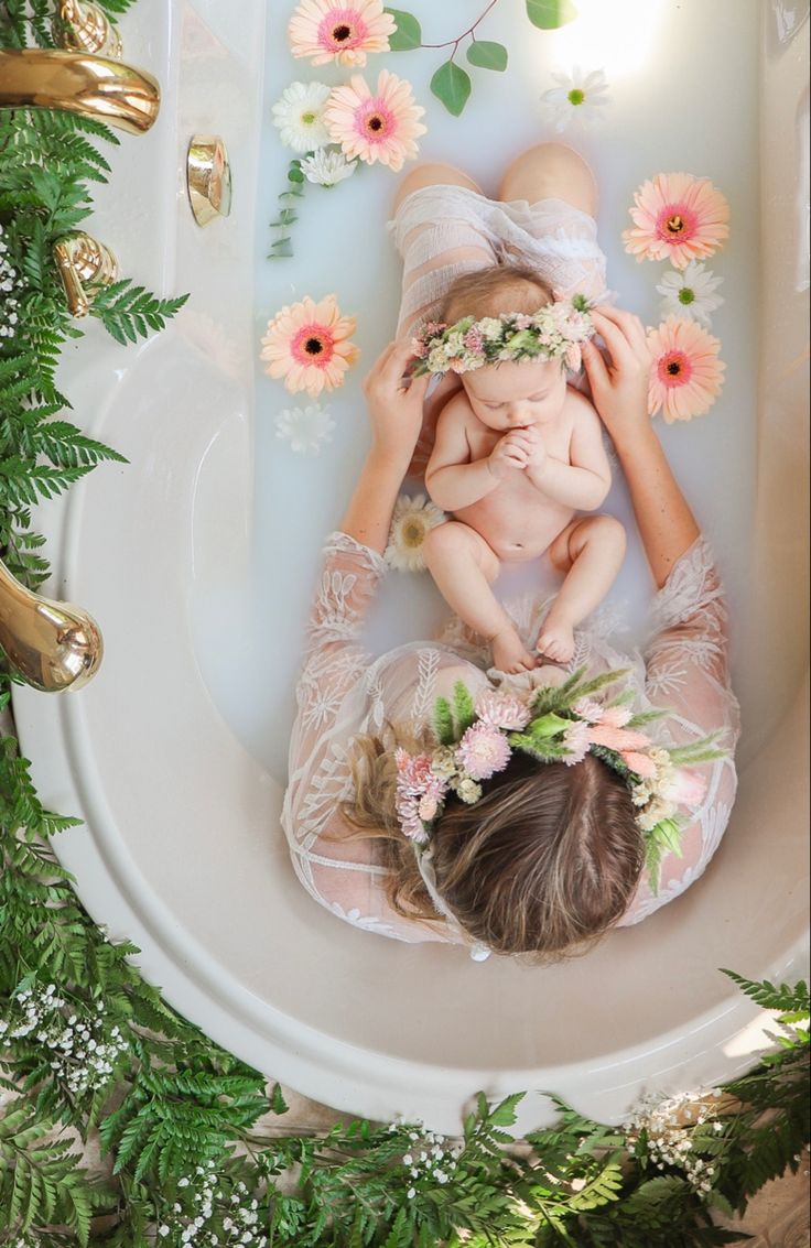 an overhead view of two women and a baby in a bathtub surrounded by flowers