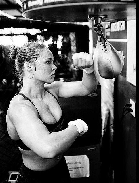 a woman in black and white boxing gloves on the punching bag with her arm stretched out