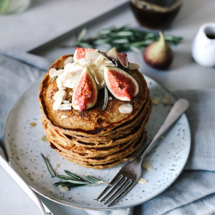 a stack of pancakes topped with figs and whipped cream