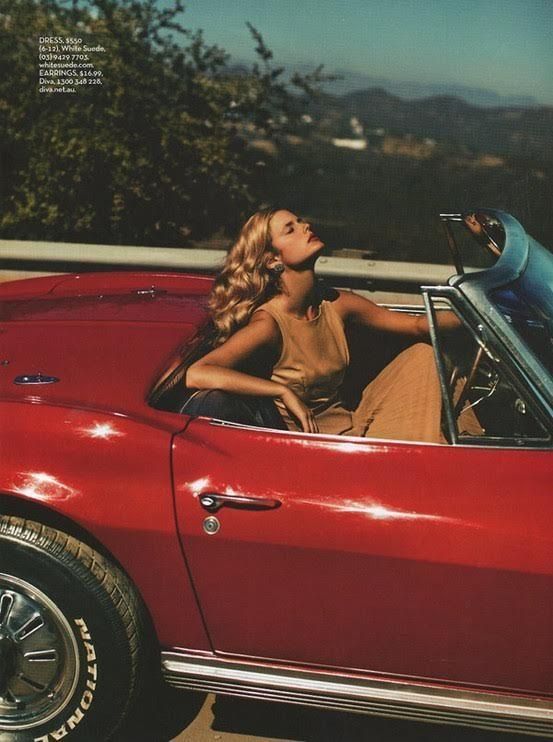 a woman sitting in the driver's seat of a red car with stars all over it