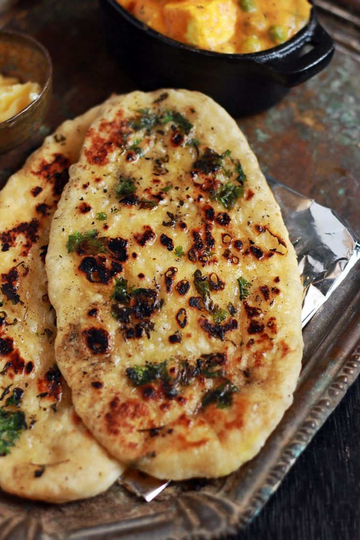 two flat breads are sitting on a plate next to bowls of potatoes and other food