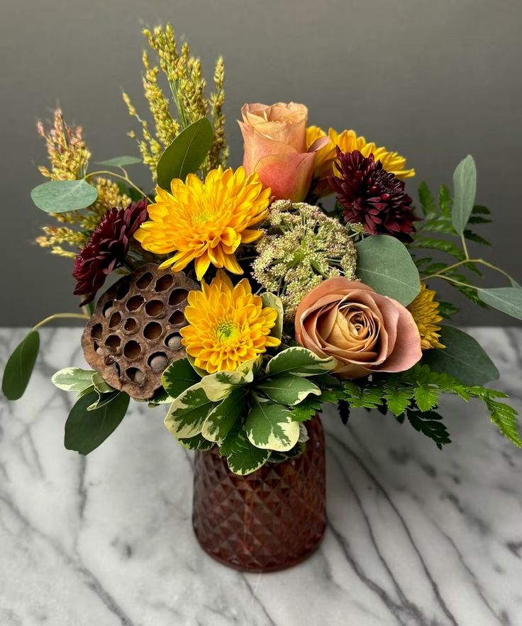 a vase filled with lots of flowers on top of a marble countertop next to a wall