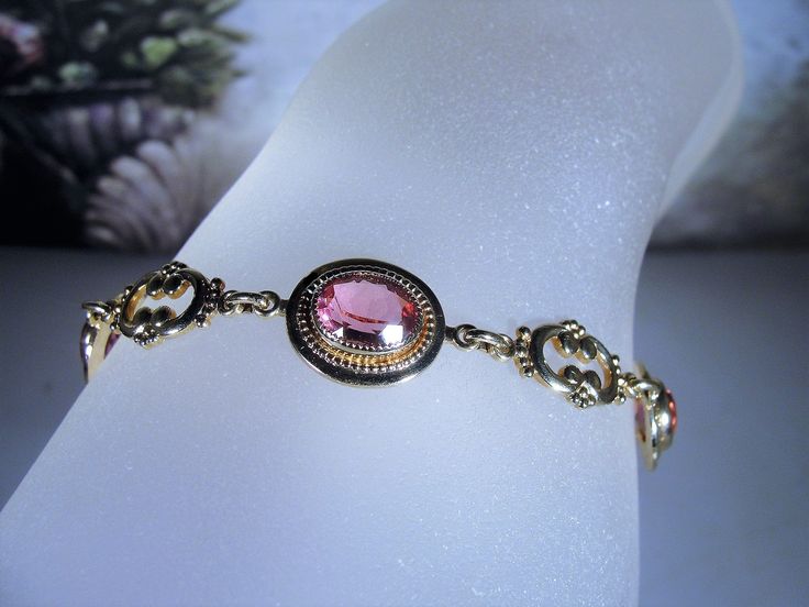 "This is a beautiful rose pink bracelet that is 14k Gold Filled. There are 4 oval cut faceted rosy pink glass gems with a decorative scroll link in between each. The look is stunning! Size of the bracelet is 7.25 inches. It has a round twist closure and a safety chain that is also able to be released and attached with the same type of closure. *Hang Tag reads: AMCO, 1/20 14K Gold Filled *Length is 7.25 inches *Width is .5 inches *Condition is Excellent = in \"LIKE NEW\" Condition; Pre-owned To v Adjustable Pink Gold Bracelets For Formal Occasions, Adjustable Pink Gold Bracelet For Formal Occasions, Pink Bangle For Formal Occasions, Pink Bangle Bracelet For Formal Occasions, Pink Formal Bangle Jewelry, Elegant Rose Gold Bracelet For Formal Occasions, Formal Pink Gold Bangle Jewelry, Elegant Pink Gold Bracelet For Formal Occasions, Adjustable Classic Pink Bracelets