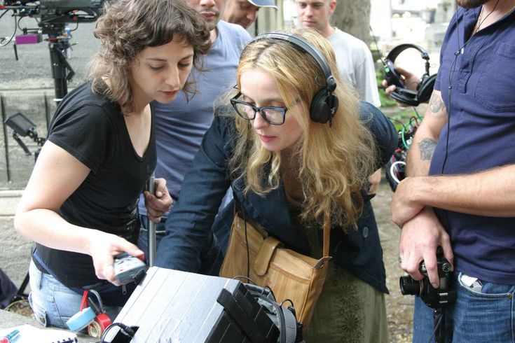 a group of people standing around each other with headphones on their ears and one woman holding a camera