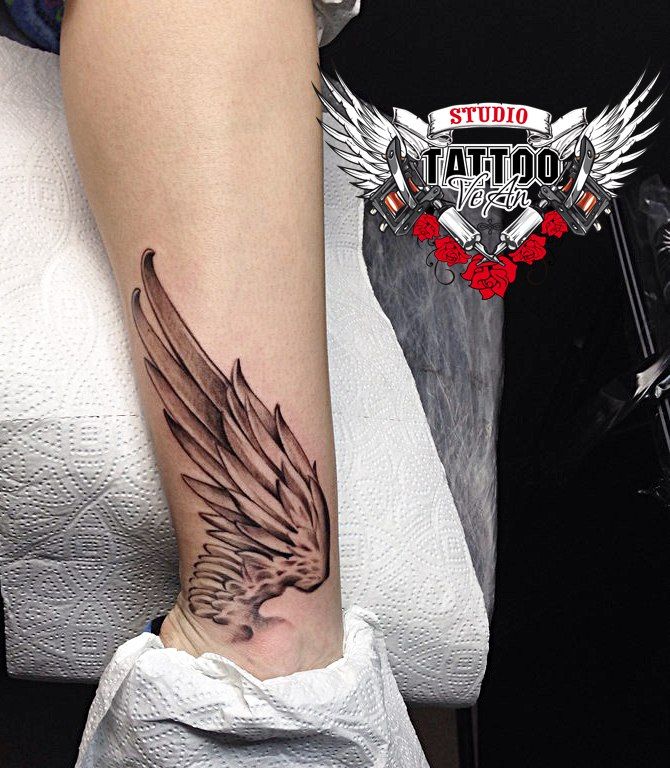 a woman's leg with a tattoo on it that has an angel wing and roses