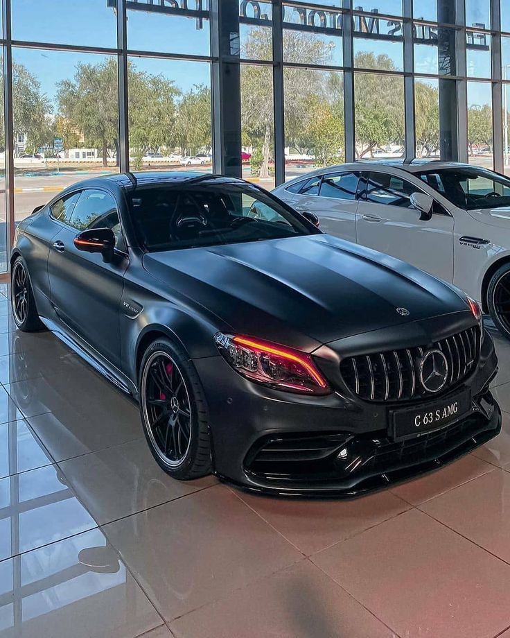 two mercedes cars are parked in front of large windows