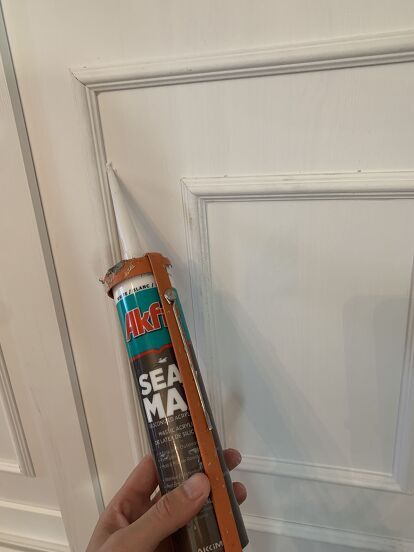 a person holding a can of sealant in front of a door with a handle