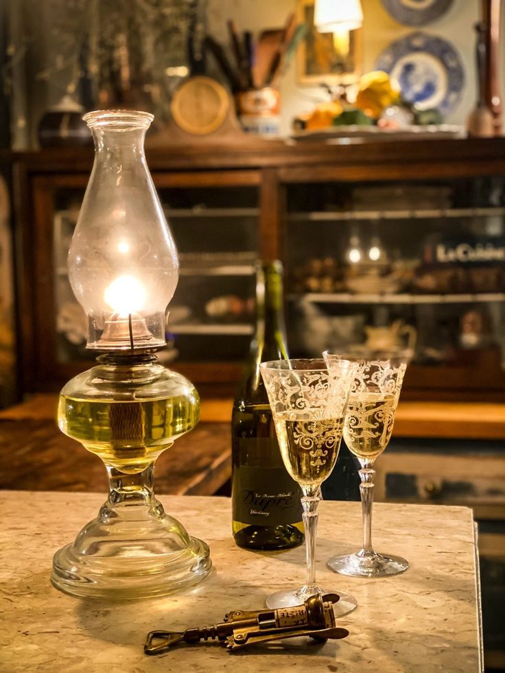 two wine glasses sitting on top of a counter next to a bottle and glass goblet