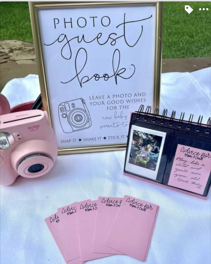 a table topped with pink cards and pictures next to a sign that says photo guest book