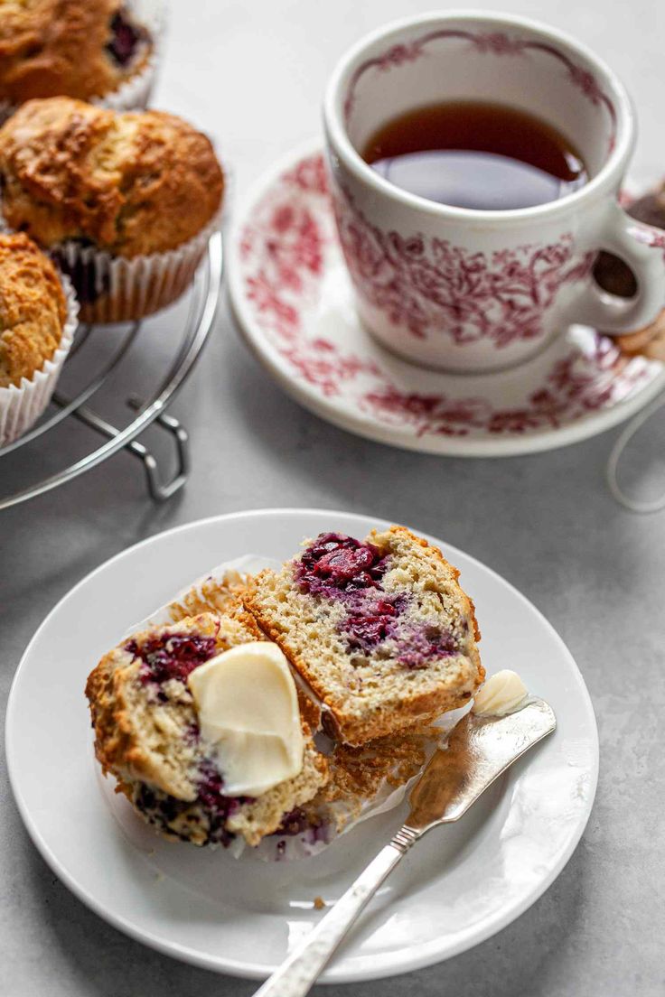 muffins with butter and jam on a plate next to a cup of tea