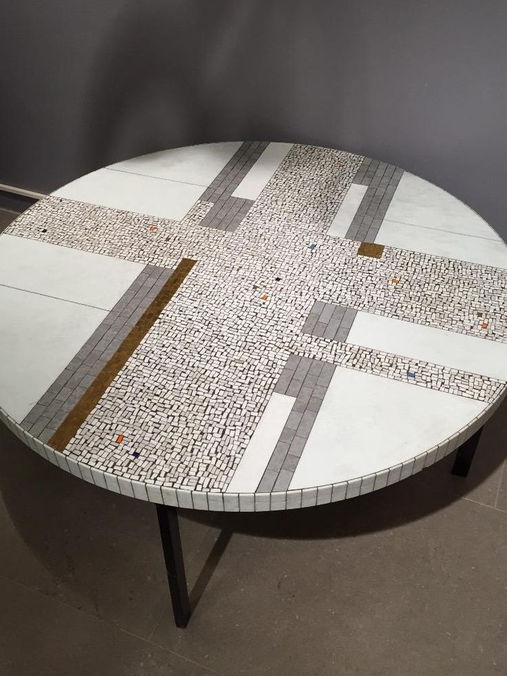 a white table with brown and black designs on it's top, sitting in front of a gray wall