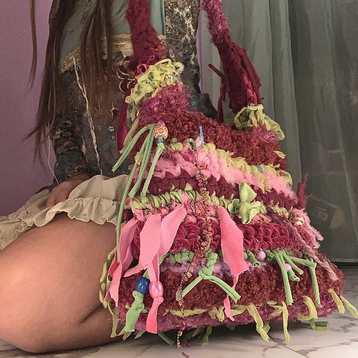 a woman is sitting on the floor with a handbag made out of crochet