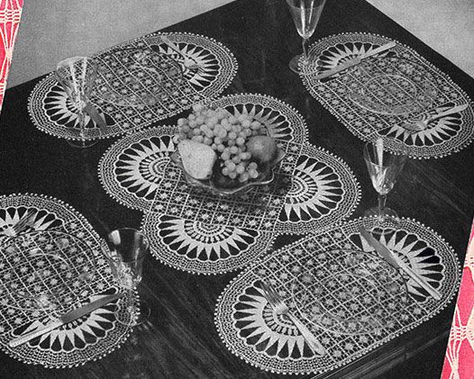 the table is set with placemats and wine glasses on it, along with grapes in a bowl